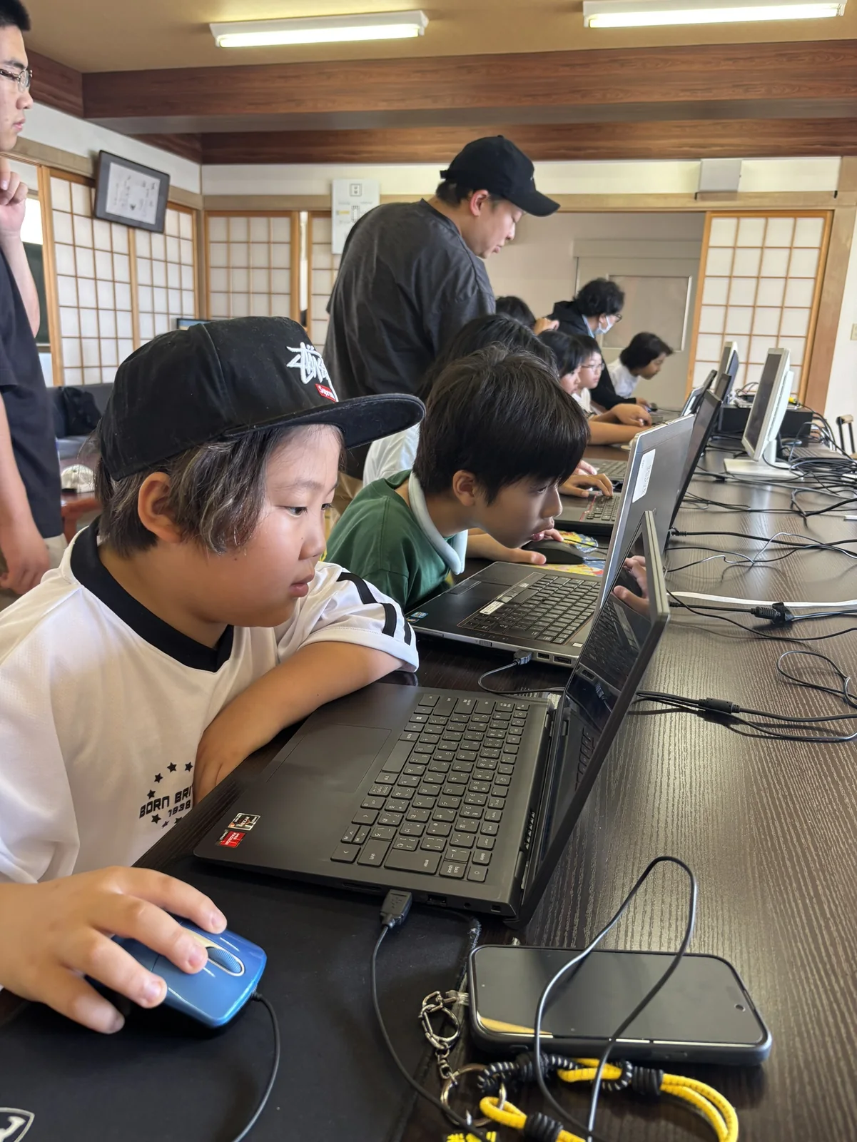 講師のサポートを受けながら、子どもたちがパソコンでデジタル作品づくりに取り組む様子